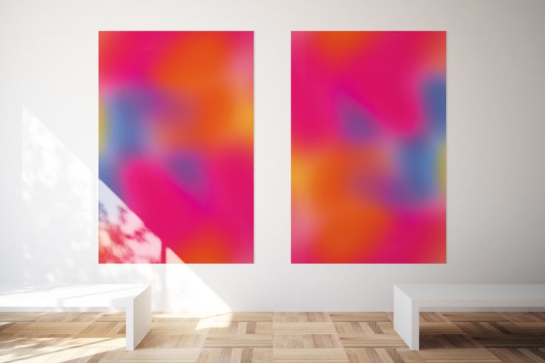 May include: Two abstract paintings with a blurred, colorful design. The paintings are in shades of pink, orange, blue, and purple. The paintings are hanging on a white wall in a gallery setting.