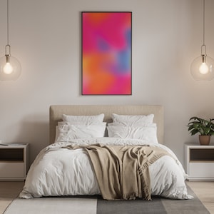 May include: A bedroom with a white bed, a tan blanket, and two white nightstands with lamps. A framed abstract painting with pink, orange, and blue colors hangs on the wall above the bed.