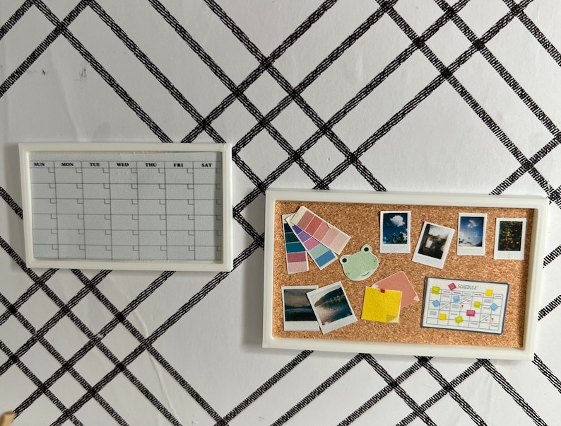 May include: A white framed corkboard with a variety of items pinned to it, including photos, a color palette, a frog sticker, and a small calendar with the word "Schedule" printed on it. There is also a white framed calendar with the days of the week labeled.