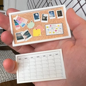 May include: A white corkboard with a frog, a color palette, photos, and a schedule planner. Below is a white dry erase calendar with the days of the week labeled.