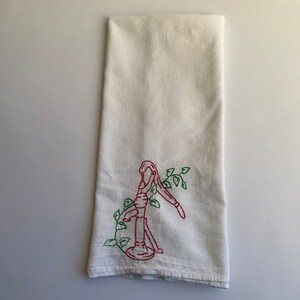 May include: White kitchen towel with red and green embroidery of a hand pump with vines.