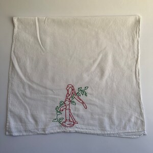 May include: White kitchen towel with red and green embroidery of a hand pump with vines.