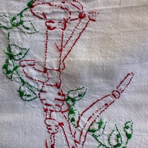 May include: White fabric with red and green embroidery of a flower with a stem and leaves.
