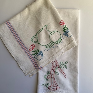 May include: Two white tea towels with embroidered designs. One towel features a pitcher, a bowl, and a flower in a pot. The other towel features a hand pump with vines. Both towels have red, blue, and green embroidery.
