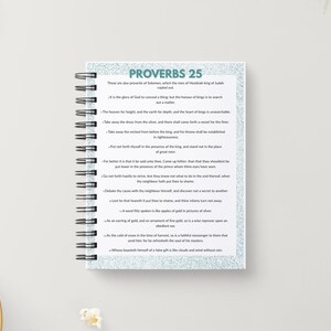 May include: A spiral-bound notebook with the text "PROVERBS 25" in teal. The notebook's pages contain printed text. A pencil and a bowl of popcorn are in the background.