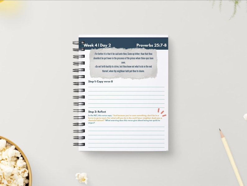 May include: A white spiral-bound notebook with text and lined pages. The top section reads "Week 4 | Day 2" and "Proverbs 25:7-8". The open page contains text and prompts for reflection. A pencil and a bowl of popcorn are also visible.