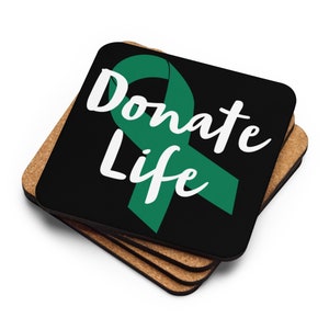 May include: Set of four black coasters with a green ribbon and the text "Donate Life" in white. The coasters are made of cork.