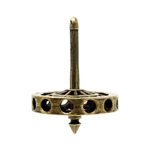 May include: A gold-colored metal spinning top with a circular base and a pointed tip. The base has a series of holes around the edge.