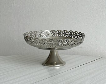 Verzilverde metalen schaal op voet met opengewerkte bloem- en spitsboogrand, elegante decoratieve compoteschaal met opengewerkte details