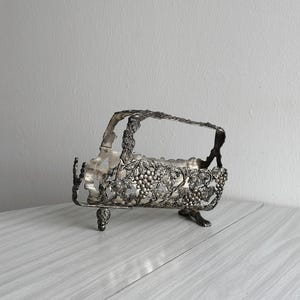 Antique silver metal bottle holder decorated with bunches of grapes, refined wine holder, elegant table piece