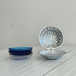 ガラスインサート付きの光沢のあるステンレススチール製のシェル型バターディッシュ。エレガントなアイテム、シックなテーブルデコレーション、洗練されたギフトアイデア、多目的に使えます。