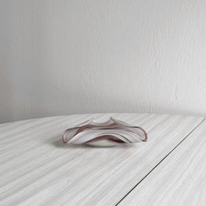 May include: A white and purple glass ashtray with a wavy design.