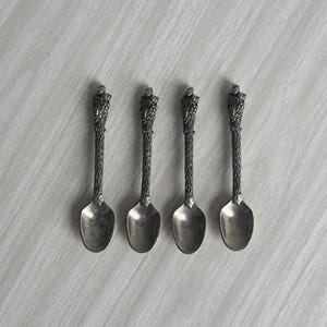Peut inclure: Ensemble de quatre cuillères en argent avec un design unique de branche d'arbre. Les cuillères ont un bol arrondi et un manche détaillé qui ressemble à une branche d'arbre.