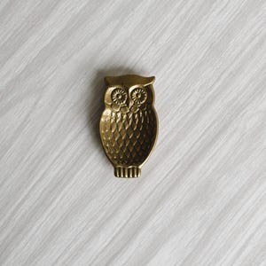 May include: A gold owl-shaped trinket dish with a textured surface.