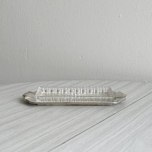 May include: A set of three ceramic mugs with a speckled, cream-coloured glaze. Each mug features a different hand-painted design: a blue and green leaf, a yellow flower, and a red berry. The mugs have a simple, rounded shape and a comfortable handle.