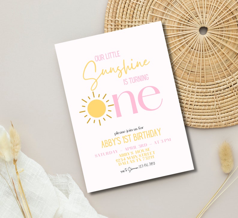 K&ouml;nnte beinhalten: Eine wei&szlig;e Einladungskarte mit einem pinkfarbenen und gelben Sonnenmotiv. Der Text lautet "Our Little Sunshine is Turning One" und enth&auml;lt Details zur 1. Geburtstagsfeier von Abby.