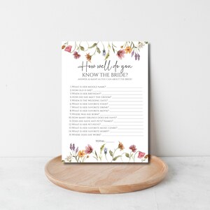 May include: A printable bridal shower game with a floral border. The game asks guests to answer questions about the bride, such as her middle name, age, birthday, and favorite food. The game includes a space for guests to write their answers and a total score.
