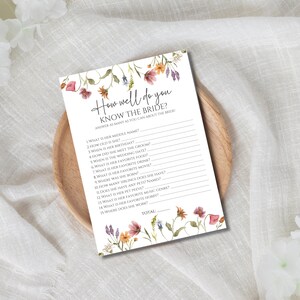 May include: A printable bridal shower game with a floral design. The game asks guests to answer questions about the bride, such as her middle name, birthday, and favorite movie. The game includes a space to calculate the total number of correct answers.