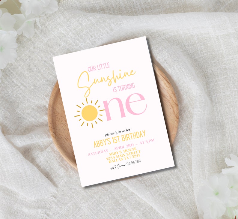 K&ouml;nnte beinhalten: Eine rosafarbene und gelbe Geburtstagseinladung mit einer Sonnendarstellung und dem Text "Our Little Sunshine is Turning One". Die Einladung enth&auml;lt die Details f&uuml;r Abbys 1. Geburtstagsparty, einschlie&szlig;lich Datum, Uhrzeit und Ort.