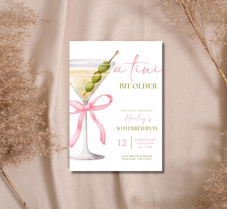 May include: A white invitation card with a pink ribbon and a martini glass with green olives. The text on the card reads "a tini bit older" and "Hailey's 30th Birthday".