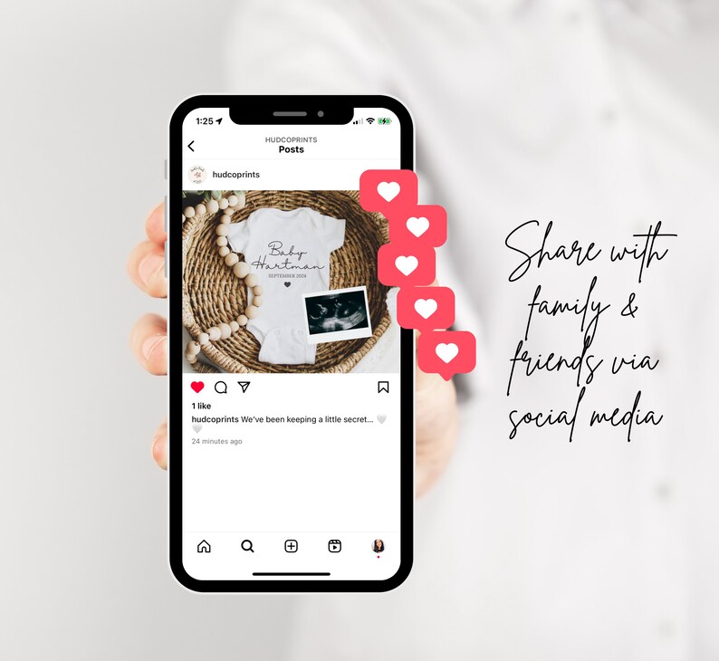May include: A smartphone screen displaying a social media post announcing a pregnancy. The post features a white onesie with the text "Baby Hartman" and a sonogram photo. The post has received one like and a comment that reads "We've been keeping a little secret..." The post is accompanied by a series of red heart icons.