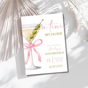 May include: A white invitation card with a watercolor illustration of a martini glass with olives and a pink ribbon. The text on the card reads "a  tini bit older" and "Hailey's 30th Birthday". The invitation includes the date, time, and location of the event.