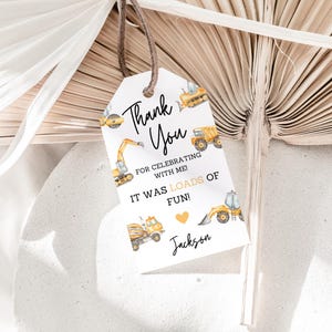 May include: Thank you for celebrating with me! It was loads of fun! A white tag with black and yellow text, featuring a heart and illustrations of construction vehicles. The text reads "Thank You for celebrating with me! It was loads of fun!" and "Jackson".