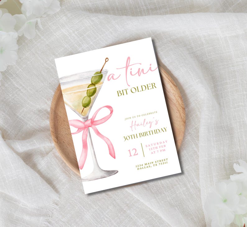 May include: A white invitation card with a pink ribbon and a martini glass with green olives. The text on the card reads "a tini bit older" and "Join us to celebrate Hailey's 30th Birthday".