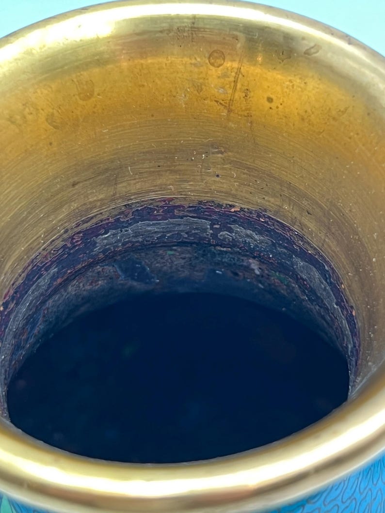 Puede incluir: Primer plano del interior de un jarr&oacute;n decorativo. El borde superior es de color dorado brillante y el interior es azul oscuro. El jarr&oacute;n tiene un dise&ntilde;o detallado en el exterior, con una combinaci&oacute;n de colores azul y dorado.