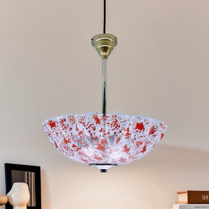 May include: A white and red patterned glass pendant light fixture with a gold metal canopy and a silver chain.