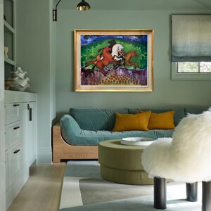 May include: An interior shot of a living room with a framed painting of horses. The painting has a gold frame and depicts horses in motion against a green and blue background. The room features a teal sofa, yellow pillows, and a green ottoman.