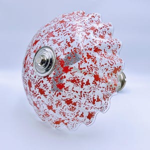 May include: A white glass lampshade with a red splatter pattern and a scalloped edge.