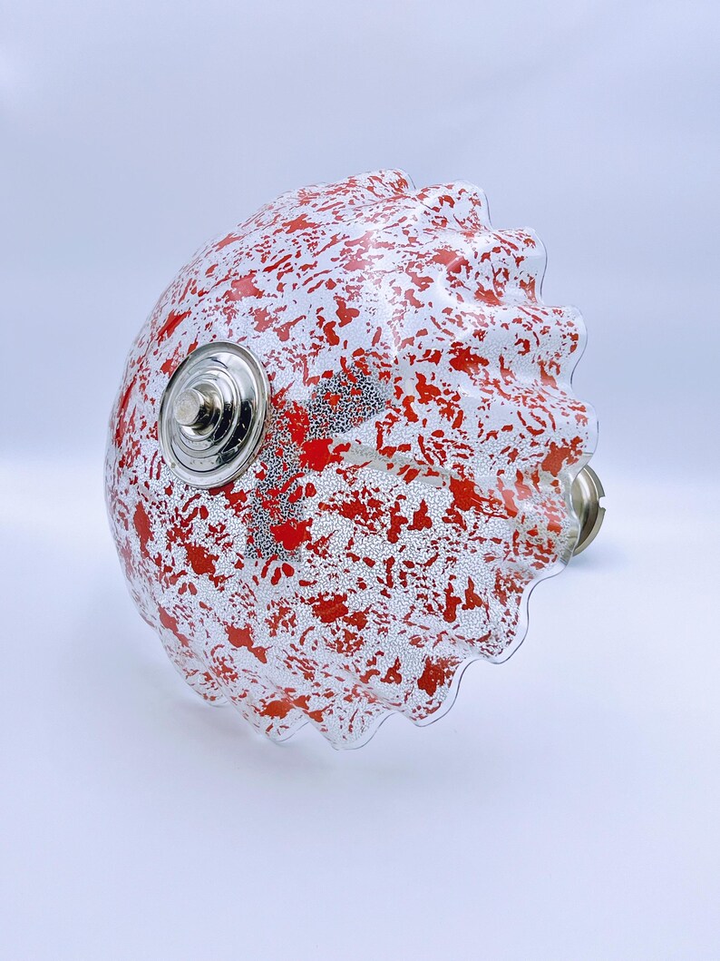 May include: A white glass lampshade with a red splatter pattern and a scalloped edge.