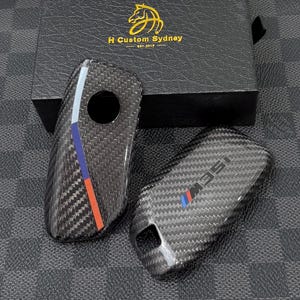 May include: A white ceramic mug with a black handle and the text "But First, Coffee" in a handwritten style. The mug is on a white surface. The mug is approximately 10 cm tall.