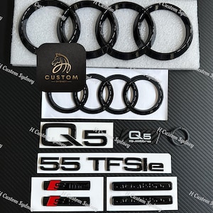 May include: A selection of black car emblems and badges, including the Audi rings logo, Q5, 55 TFSIe, and S line badges. The image also features a black leatherette tag with a gold horse logo and the text "CUSTOM SYDNEY".