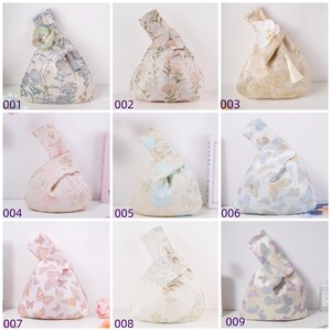 May include: Nine fabric knot bags in various floral and butterfly patterns. Each bag has a unique design, with colors ranging from light blue and pink to cream and gold. Some bags feature decorative accents.