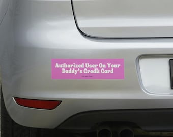 May include: A pink bumper sticker with white text that reads "Authorized User On Your Daddy's Credit Card".