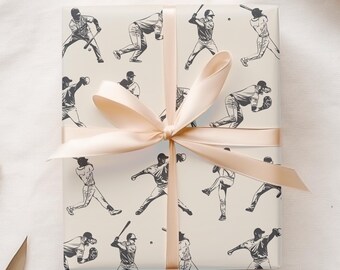 May include: White gift wrap with a repeating pattern of black and white baseball players. The gift wrap is tied with a beige ribbon.