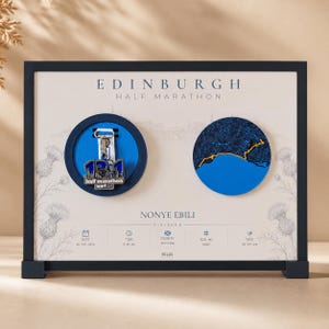 May include: A framed Edinburgh Half Marathon display featuring a medal with a 13.1 graphic, a circular map of the race route, and personalised text including the name Nonye Ebili, date 26 May 2024, time 2:05:45, bib number 34987, and pace 09:37/mi.