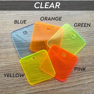 Puede incluir: Una colecci&oacute;n de etiquetas de acr&iacute;lico transparentes y coloridas en azul, naranja, verde, rosa y amarillo. Cada etiqueta tiene forma cuadrada con un peque&ntilde;o agujero rectangular. La palabra "CLEAR" est&aacute; en la parte superior.