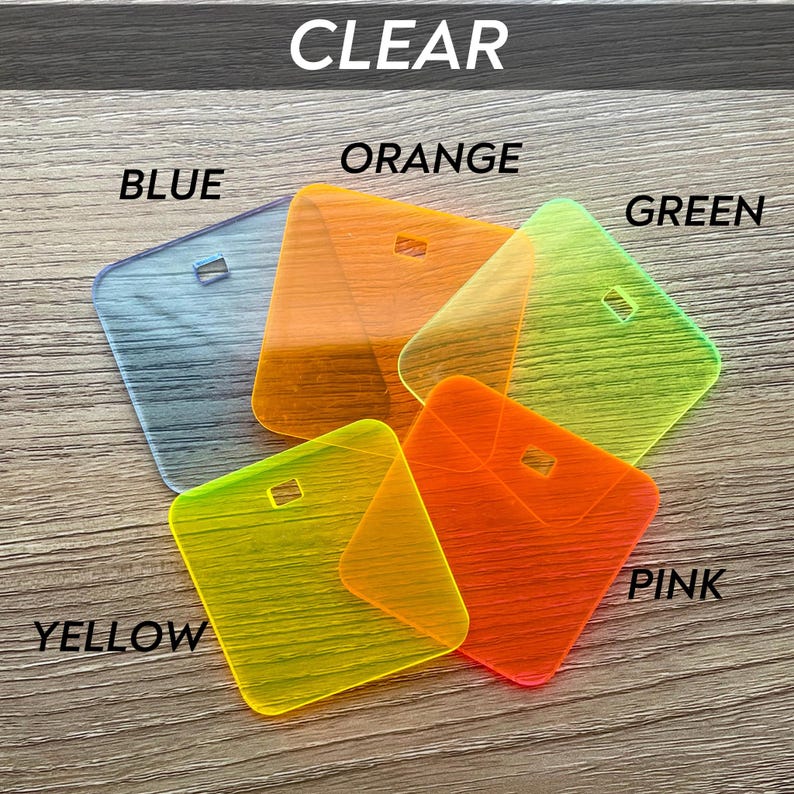 Puede incluir: Una colecci&oacute;n de etiquetas de acr&iacute;lico transparentes y coloridas en azul, naranja, verde, rosa y amarillo. Cada etiqueta tiene forma cuadrada con un peque&ntilde;o agujero rectangular. La palabra "CLEAR" est&aacute; en la parte superior.