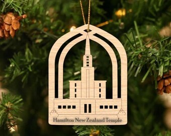 Puede incluir: Adorno navideño de madera con un diseño recortado del Templo de Hamilton en Nueva Zelanda. El adorno es de color marrón claro y tiene una cuerda dorada para colgar.