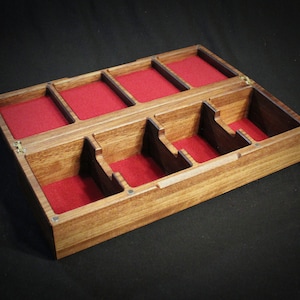 May include: A wooden box with a hinged lid, divided into compartments lined with red felt. The box is made of dark wood with a natural grain.