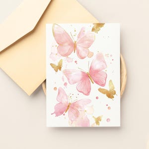 Puede incluir: Una tarjeta blanca con mariposas de acuarela rosa y dorada. Las mariposas est&aacute;n dispersas por la tarjeta con salpicaduras de pintura dorada.