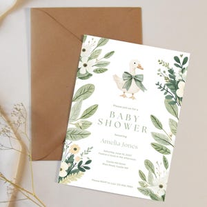 Puede incluir: Una invitaci&oacute;n para baby shower con una ilustraci&oacute;n en acuarela de un ganso con un lazo verde, rodeado de elementos florales. La invitaci&oacute;n incluye el texto "Baby Shower" y los detalles de la fiesta de Amelia Jones.