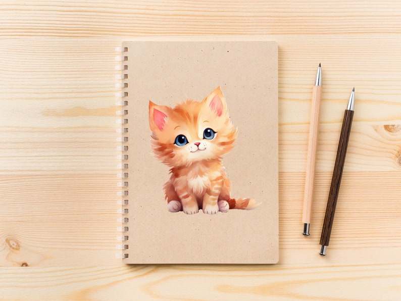 May include: A brown spiral bound notebook with a cute cartoon illustration of a ginger kitten with blue eyes. The notebook is on a light wood surface with two pens, one brown and one light wood.