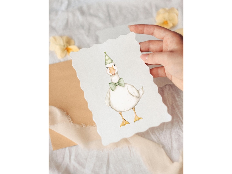 Puede incluir: Ilustraci&oacute;n en acuarela de un ganso blanco con pajarita y gorro de fiesta verdes. El ganso est&aacute; sobre una tarjeta con bordes festoneados, sostenida por una mano. Fondo suave y neutro con flores y una cinta.