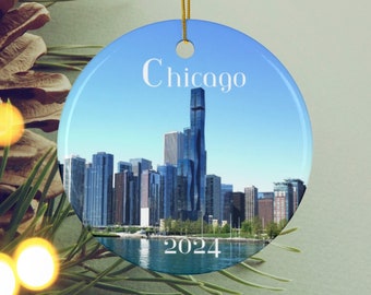 Pode incluir: Um ornamento redondo de cerâmica branca com uma imagem do horizonte de Chicago. O ornamento tem a palavra "Chicago" impressa na parte superior e o ano "2024" impresso na parte inferior.