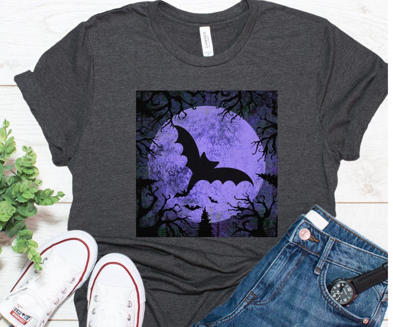 May include: A dark gray t-shirt with a purple and black graphic of a bat flying in front of a full moon. The graphic has a vintage, distressed look.