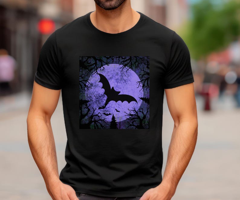 May include: Black t-shirt with a graphic print of a bat flying in front of a purple moon. The moon is surrounded by trees and the background is a dark purple.